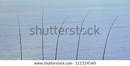 five fishing poles on the end of an ocean pier