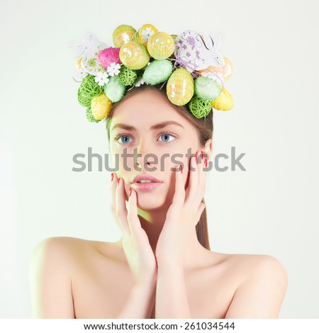 Spring Woman. Beauty model girl with colorful flowers. Easter Hair Style. Beautiful Lady with easter eggs on her head. Easter Woman.Portrait of Beautiful Model with Colorful Eggs