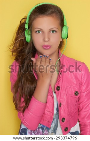 lovely teen girl in pink leather wear listening music on headphones.beautiful young girl.Green headphones