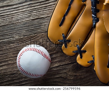 Baseball ball and glove on wood desk