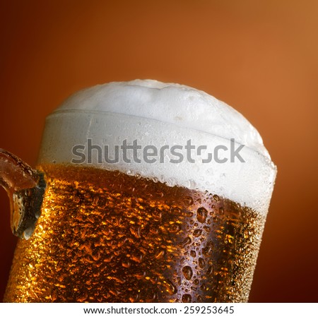 Mug of cold light beer on brown background