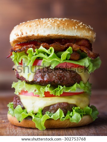 big fresh burger with cheese and bacon on wooden table