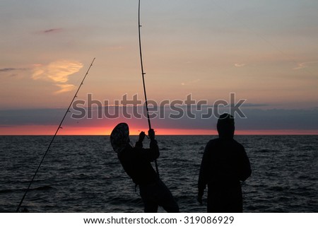 Fishermen fishing on the rock over looking Atlantic Ocean just before sunrise. Photographed near Narragansett, RI, on September 2, 2012.