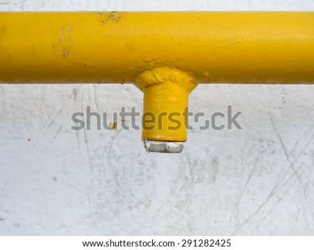 Yellow gas pipe against concrete wall
