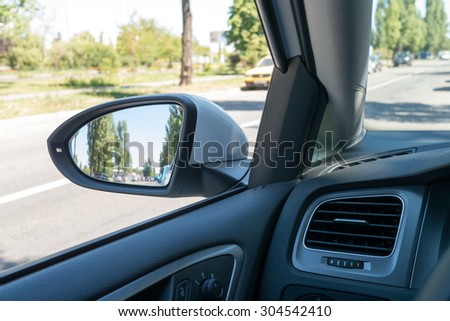 View from driver\'s seat of auto on the street and partially viewed interior of  car. Summertime. Shot with Lumix G6, 20 mm/1,7 lens.