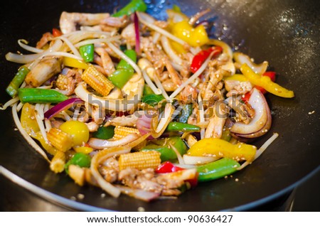 Thai stir fry chicken in a wok pan