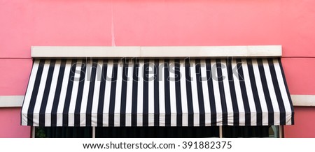 dirty black and white awning over the windows on the pink wall