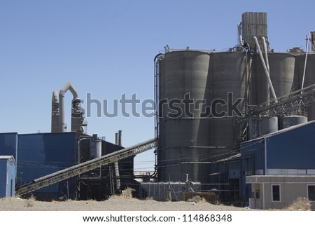 A cement plant with silos and blue skies.