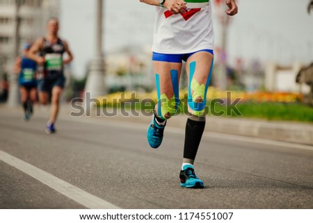 legs woman runner in compression socks and kinesio tape on knees