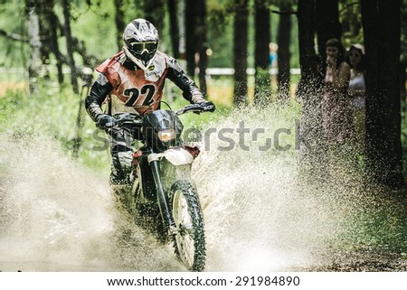 Kyshtym, Russia - June 21, 2015: Motocross driver under the spray of water during the race Urals Cup of Enduro \