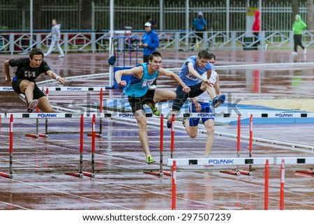 Chelyabinsk, Russia - July 10, 2015: young athletes run 110 meter hurdles  in the rain during Championship of Chelyabinsk on track and field athletics, Chelyabinsk, Russia - July 10, 2015
