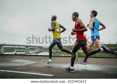 Omsk, Russia -  September 20, 2015: three leaders of the marathon running along the embankment of the Irtysh river during Siberian international marathon