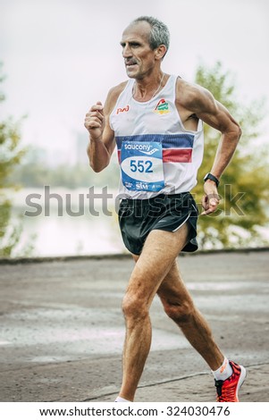 Omsk, Russia -  September 20, 2015: old man runner running along river during Siberian international marathon