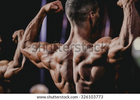 performance athlete bodybuilder to competition. demonstration of biceps your arms from behind closeup
