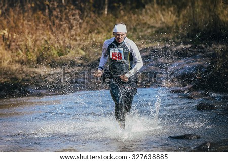 Beloretsk, Russia -  September 26, 2015: runner middle-aged man crossing river, and around him water splashes during marathon mountain \