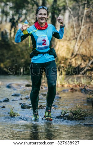 Beloretsk, Russia -  September 26, 2015: young woman runner smiling while crossing a mountain river during marathon mountain \