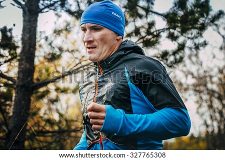 Beloretsk, Russia -  September 26, 2015: closeup of male runner of middle-aged runs through forest during marathon mountain \