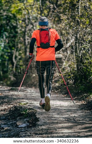 Yalta, Russia - October 31, 2015: elderly athlete man running mountain marathon along a forest trail with a backpack and walking sticks during First Yalta mountain marathon
