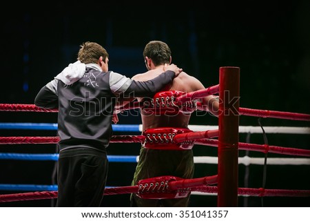 mixed martial arts fighter (MMA) stands in corner ring next to him coach. break between rounds in fight