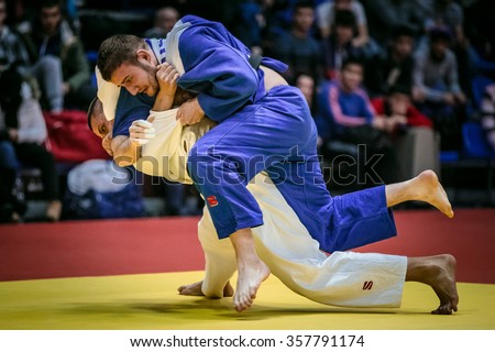 Chelyabinsk, Russia -  December 20, 2015: fight on tatami two male athletes judoists in final. in background fans during All-Russian competition on judo of memory Grigory Verichev