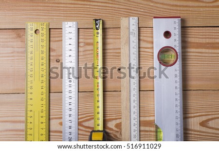 A tape measure, ruler, construction level. Various measuring tools on wooden background
