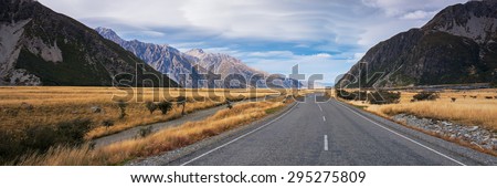 Panoramic view of long road to Mount Cook, New Zealand during autumn season. Leading line, empty road. Not centered.