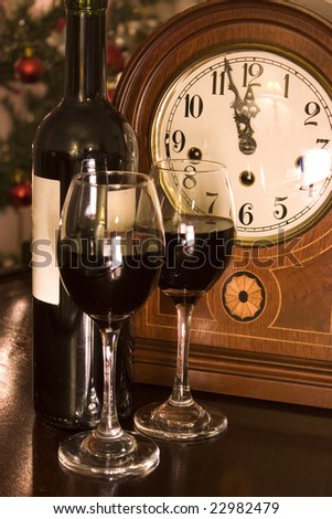 Pair of wine glasses with a clock showing the midnight, for New Year or other festivities.