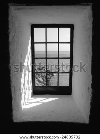 A window in a light house which faces the ocean, a framed view from a confined space
