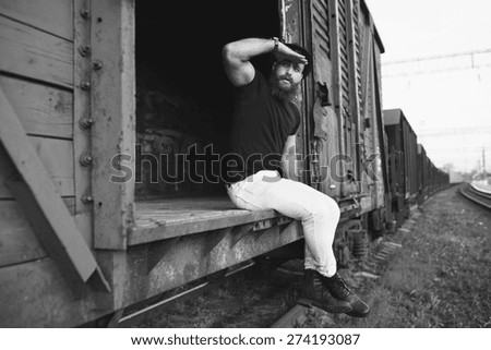 bearded man in the cap posing on the wagon train and travel, black and white