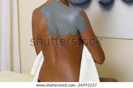 Young woman getting a mud wrap by a therapist