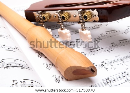Guitar and wooden flute on sheet music. Close up.
