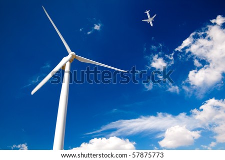 Wind turbine and white passenger airplane in the blue sky