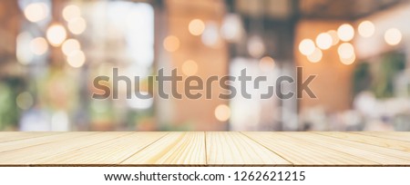 Empty Wood table top with Restaurant cafe or coffee shop interior with customer blur abstract vintage style bokeh light for montage product display background