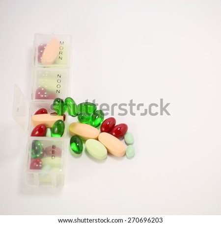 Pill box with many colorful pills and tablets isolated on white background