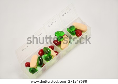Colored pills, tablets and soft gel capsules in pill box on a white background