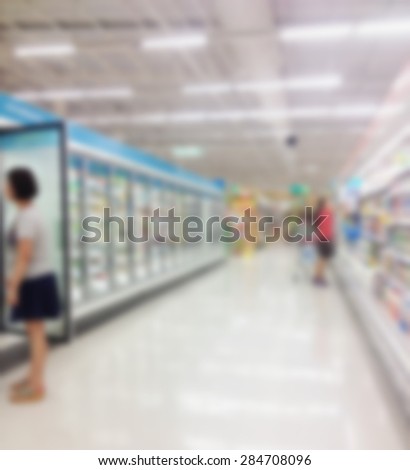 Supermarket store blur background with frozen food shelves in refrigerator and customers