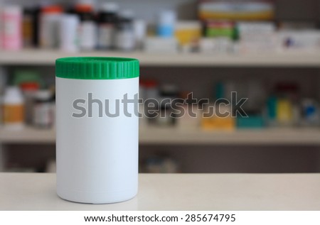 White pill bottle with pharmacy store shelves background