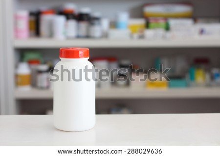 Blank white medicine bottle with blur shelves of drug in the pharmacy drugstore background