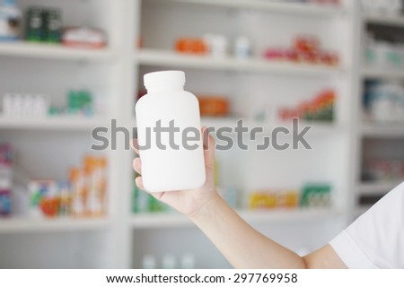 pharmacist hand holding medicine bottle in pharmacy store