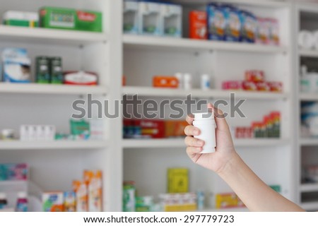 pharmacist hand holding medicine bottle in pharmacy store