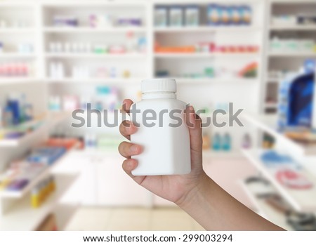 hand holding medicine bottle with blur some shelves of drug in the pharmacy drugstore