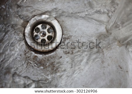 Metallic Old Kitchen sink drain swirly water flow and drops shot from above
