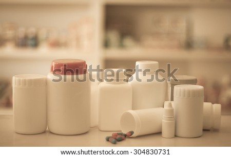 Composition of medicine bottles and pills with pharmacy store shelves background vintage filter