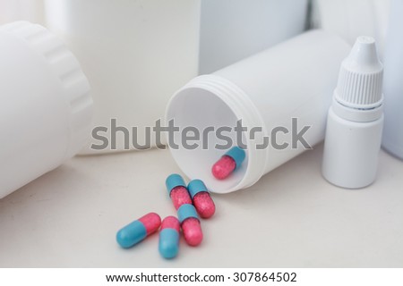 Pills spilling out of pill bottle with medicine background