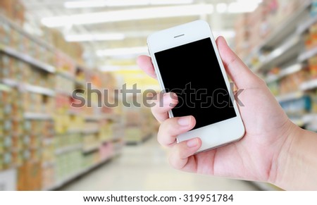 hand hold smartphone with supermarket background