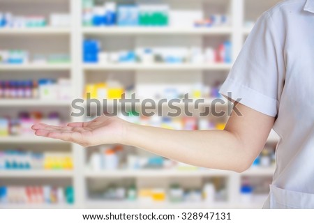 medical pharmacist woman presenting and showing copy space for product or text with blur shelves of drugs in the pharmacy