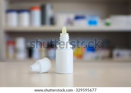 eye ear drops medicine bottle on the counter with pharmacy store shelves background