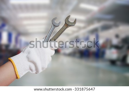 Technician holding a wrench with car repair service center background