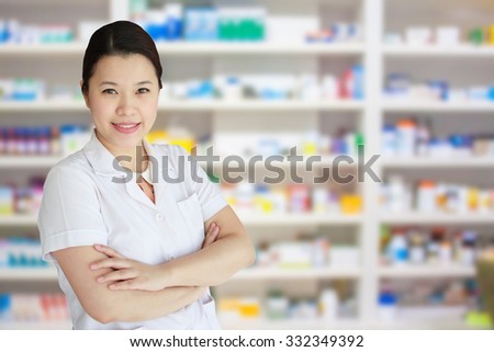 smiling asian female pharmacist with pharmacy drugstore shelves background