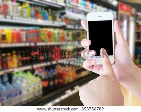 Woman hand using mobile phone while shopping in supermarket, online shopping concept